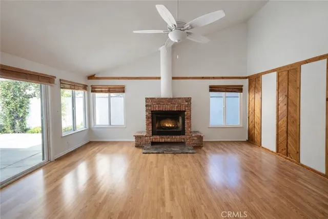 a view of a livingroom with wooden floor a fireplace and windows