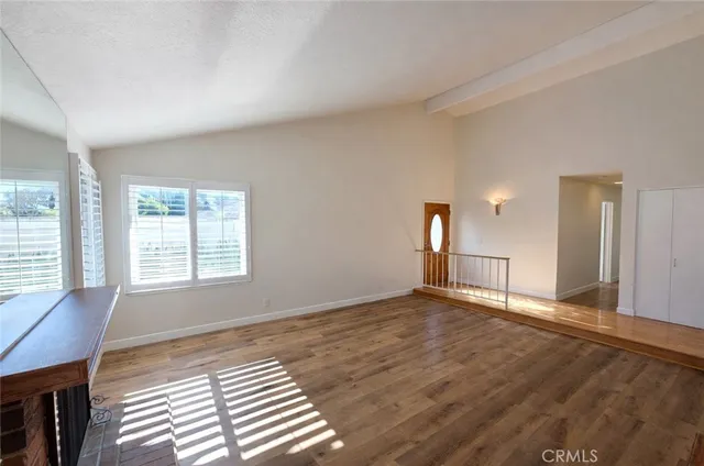 a view of an empty room with window and wooden floor