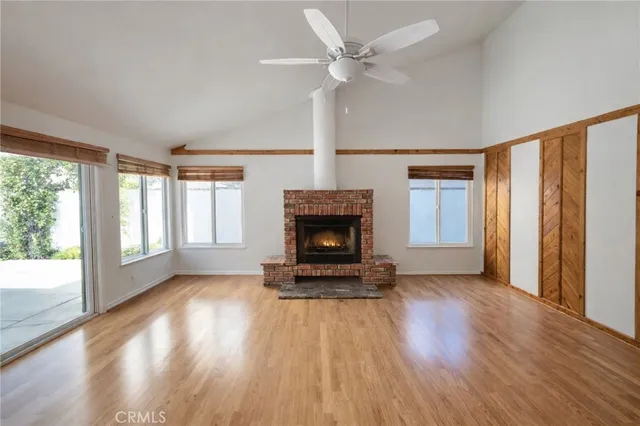 a view of a livingroom with wooden floor a fireplace and windows
