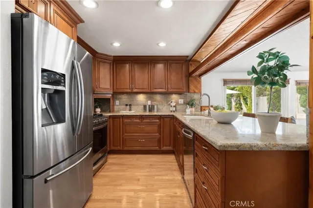 a kitchen with stainless steel appliances granite countertop a refrigerator a sink a stove and a microwave oven