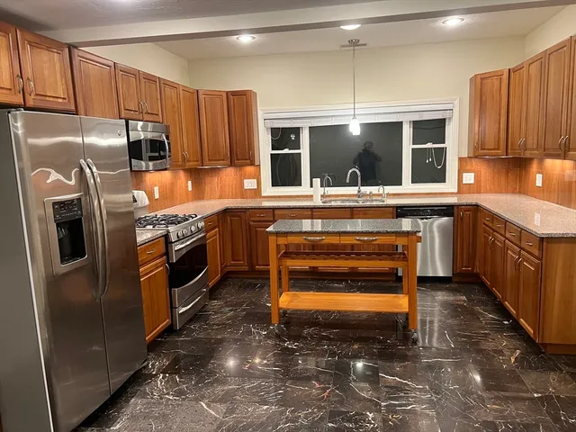 a kitchen with kitchen island granite countertop a stove oven and refrigerator