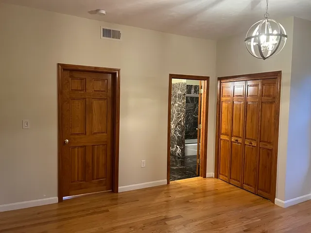 an empty room with wooden floor cabinet and windows