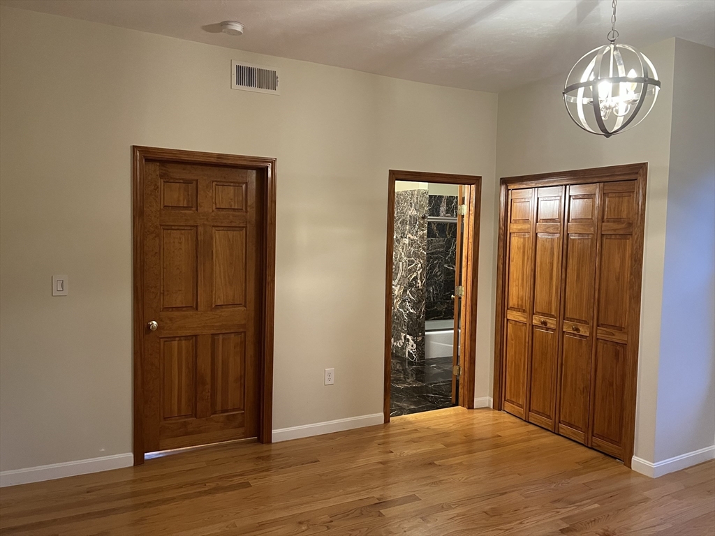194 Auburn Street, Unit 2 Newton, MA 02466 - Photo 4 of 19 an empty room with wooden floor cabinet and windows