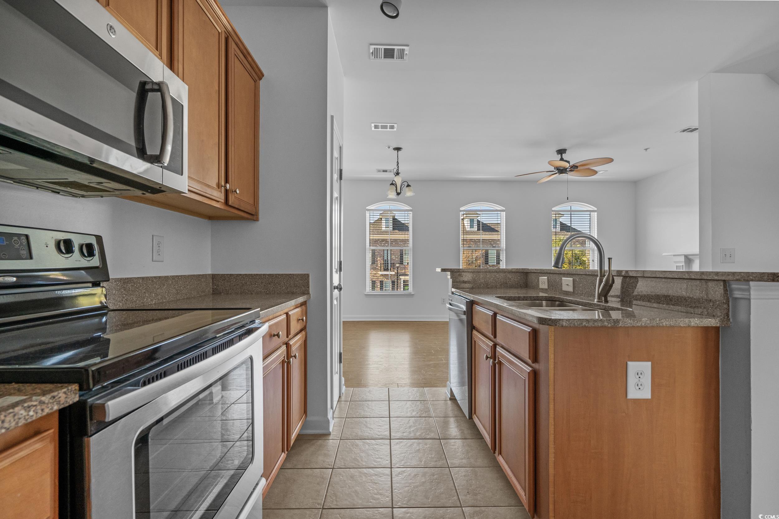 2798 Howard Avenue, Unit B Myrtle Beach, SC 29577 - Photo 15 of 40 Kitchen featuring stainless steel appliances, brown cabinets, pendant lighting, ceiling fan, and a center island with sink