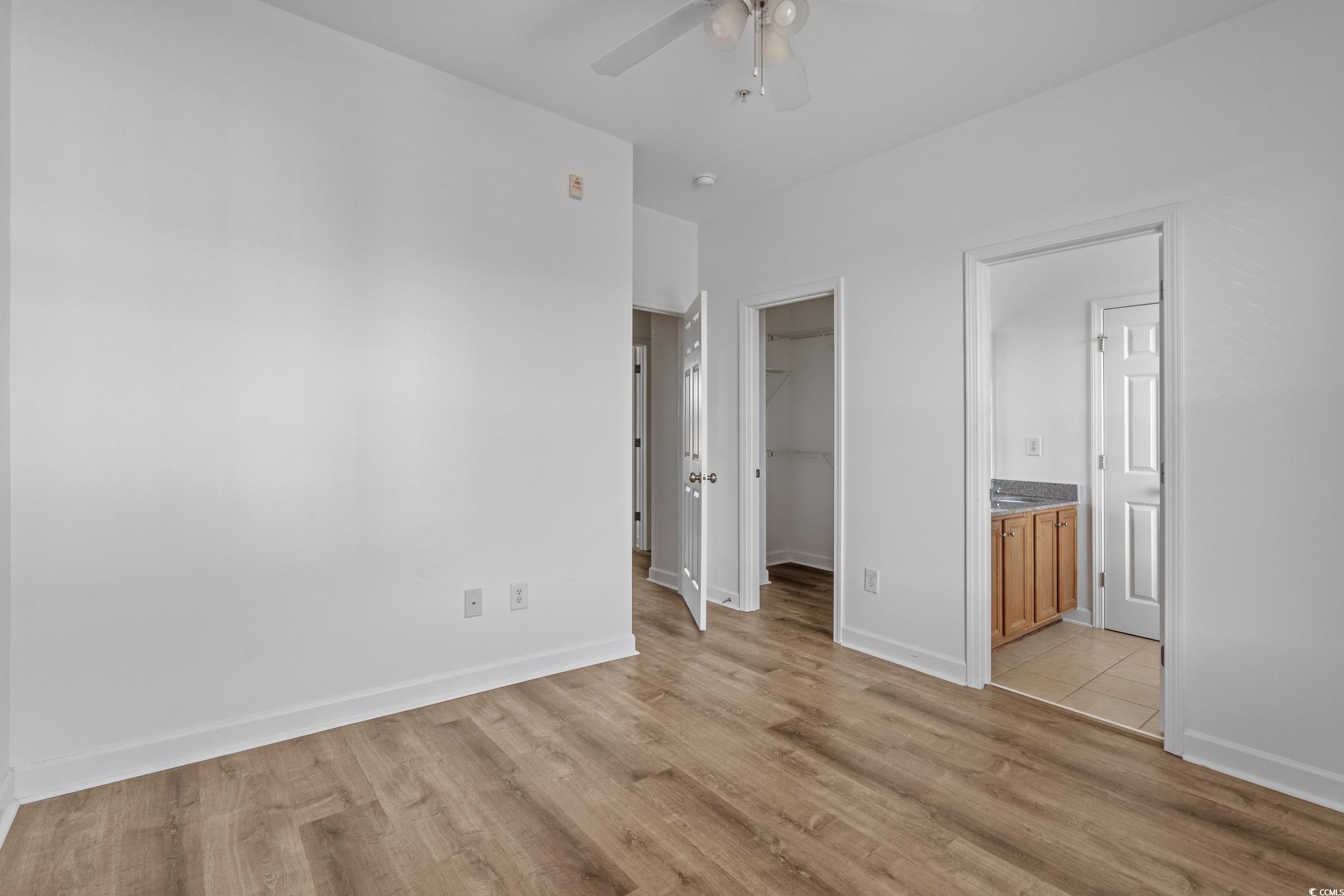 2798 Howard Avenue, Unit B Myrtle Beach, SC 29577 - Photo 19 of 40 Unfurnished bedroom featuring a walk in closet, light wood finished floors, ceiling fan, and connected bathroom