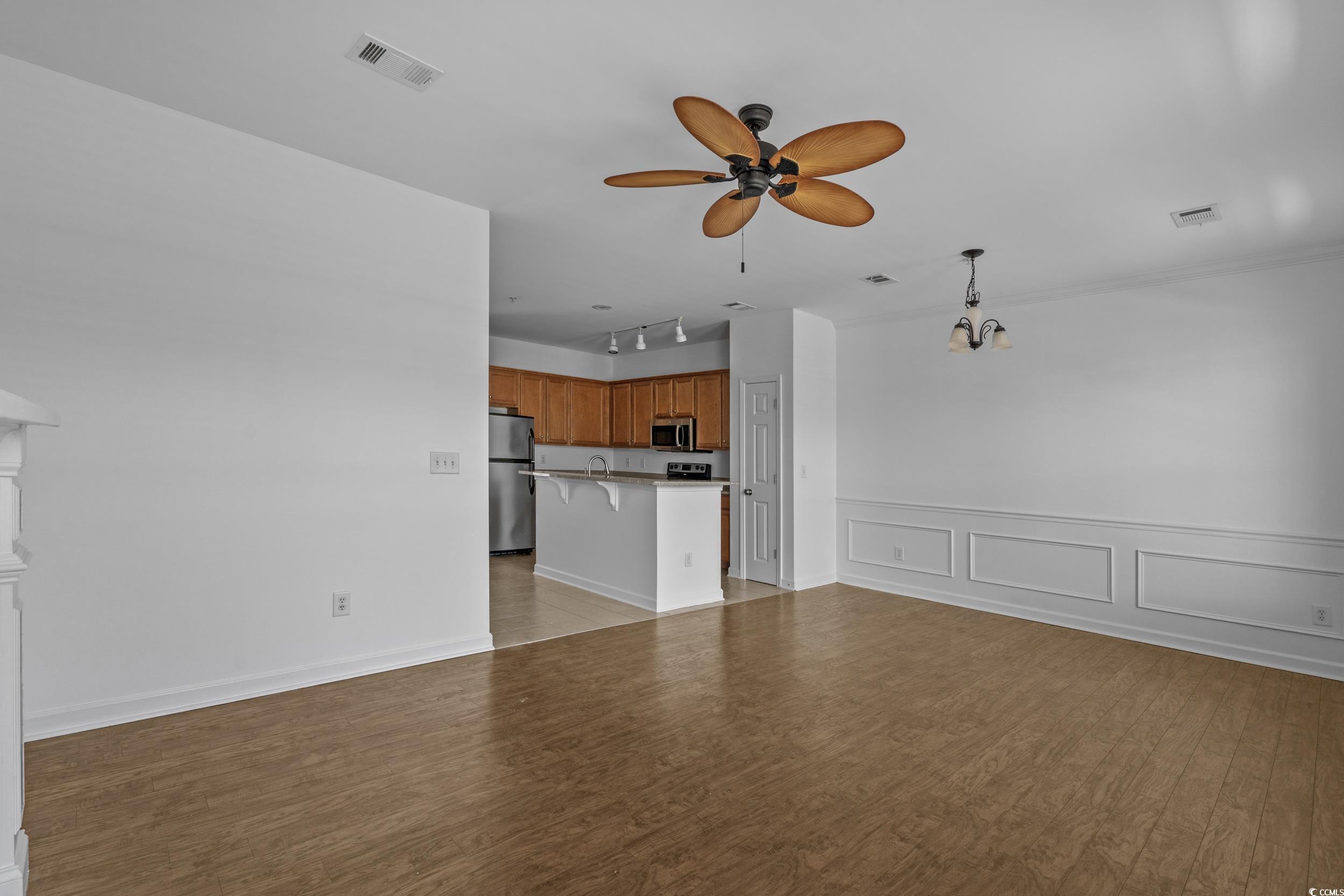 2798 Howard Avenue, Unit B Myrtle Beach, SC 29577 - Photo 8 of 40 Unfurnished living room featuring light wood finished floors, a decorative wall, rail lighting, ceiling fan, and a wainscoted wall