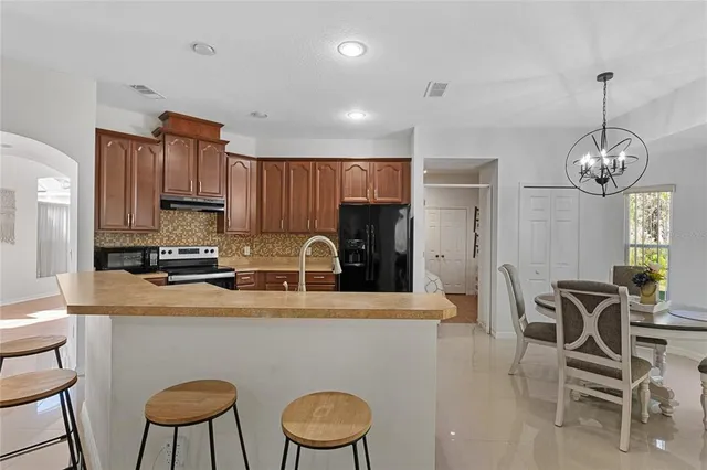 a kitchen with stainless steel appliances granite countertop a sink a stove a refrigerator cabinets and chairs