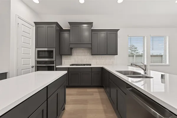 a kitchen with a sink dishwasher a stove and a refrigerator with wooden cabinet