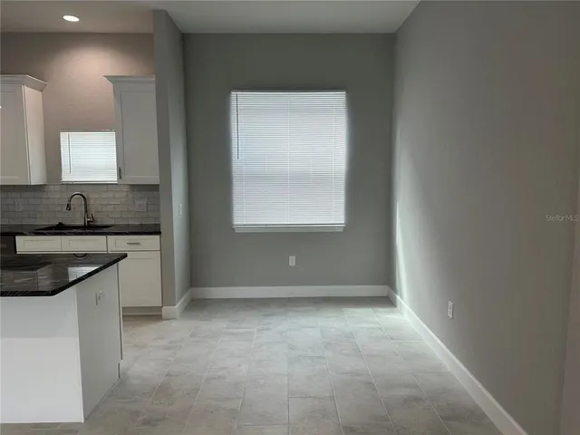 a kitchen with kitchen island granite countertop a stove top oven a sink a counter space and cabinets