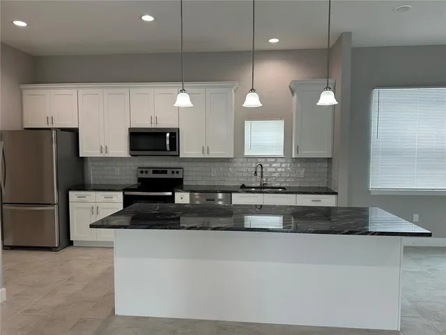 a kitchen with granite countertop white cabinets and a dishwasher