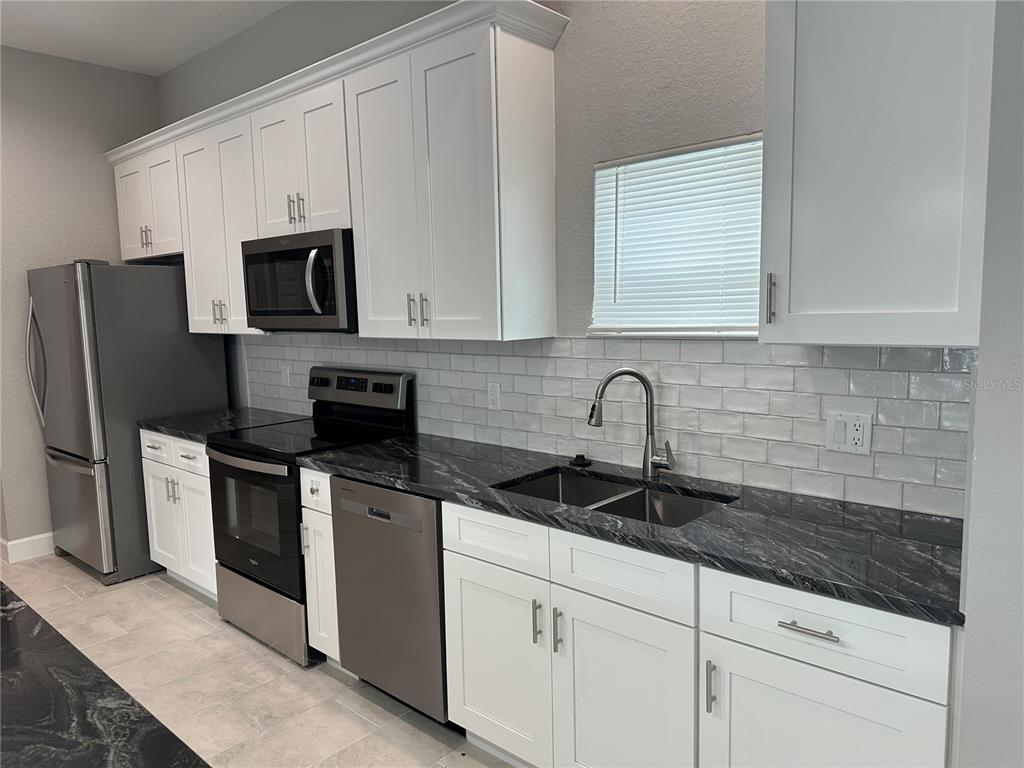4920 8th Street Zephyrhills, FL 33542 - Photo 14 of 57 a kitchen with stainless steel appliances granite countertop white cabinets a sink and a white stove