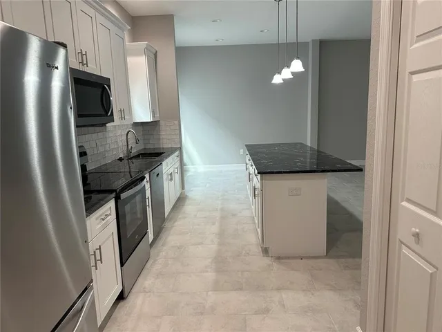 a kitchen with stainless steel appliances granite countertop a stove a sink a microwave a refrigerator and a granite counter tops