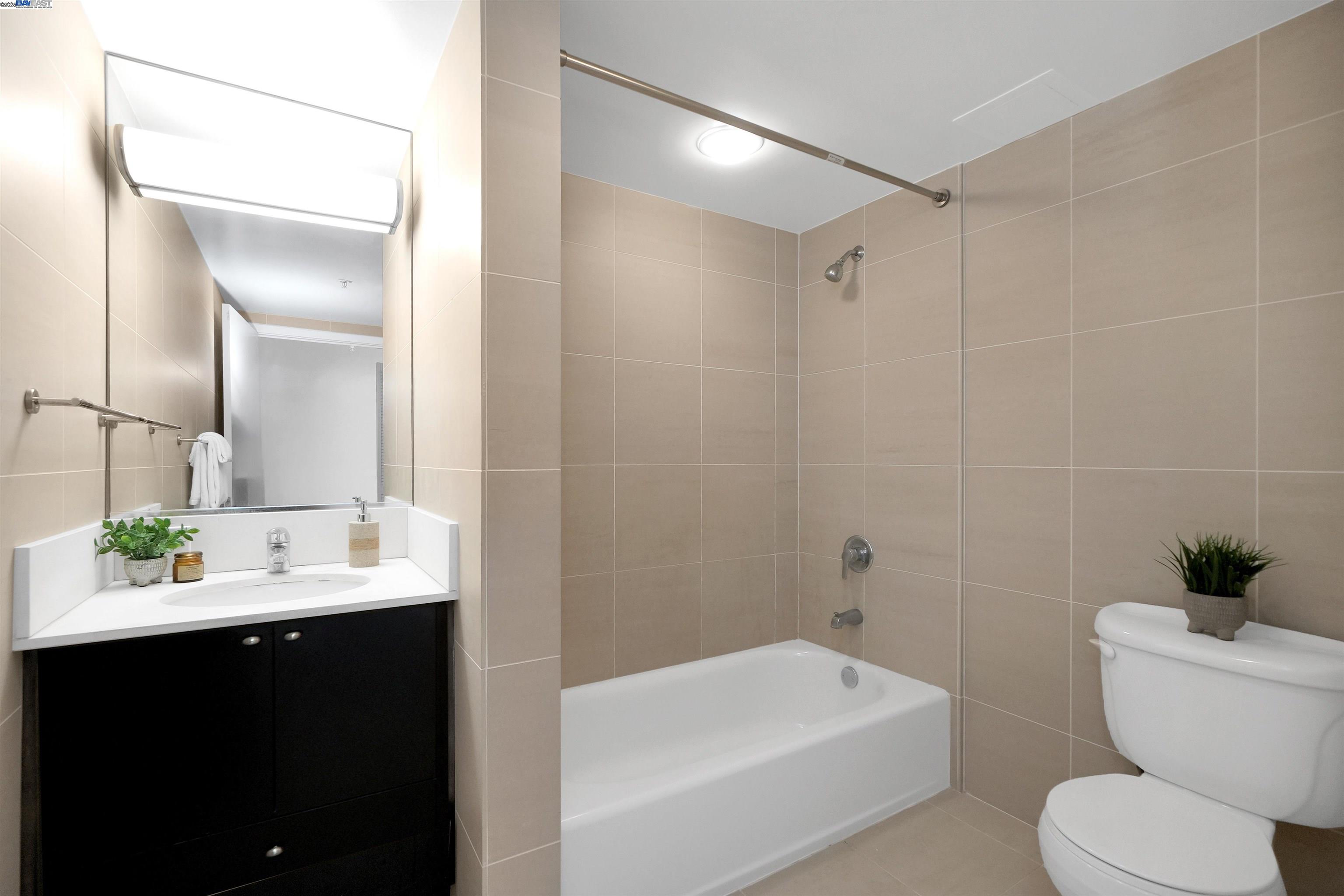 311 Oak Street, Unit PH25 Oakland, CA 94607 - Photo 5 of 14 a bathroom with a bathtub shower sink vanity mirror and toilet