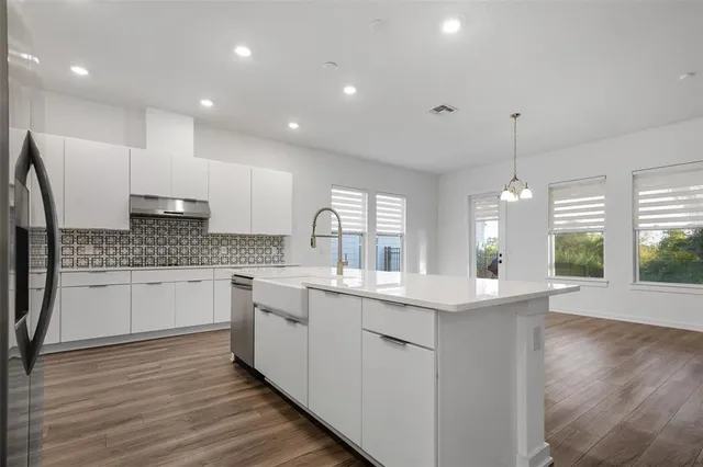 a kitchen with stainless steel appliances granite countertop a sink cabinets and wooden floor