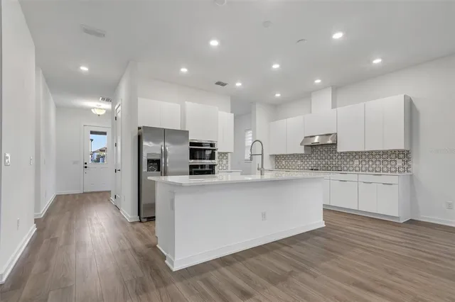 a large kitchen with stainless steel appliances kitchen island granite countertop a stove a sink and a refrigerator