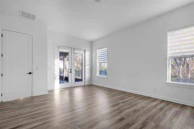 a view of an empty room with wooden floor and a window