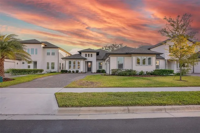 a view of a white house with a swimming pool and a yard with plants
