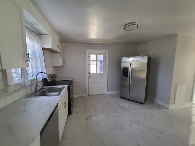 a kitchen with stainless steel appliances granite countertop a sink and a refrigerator