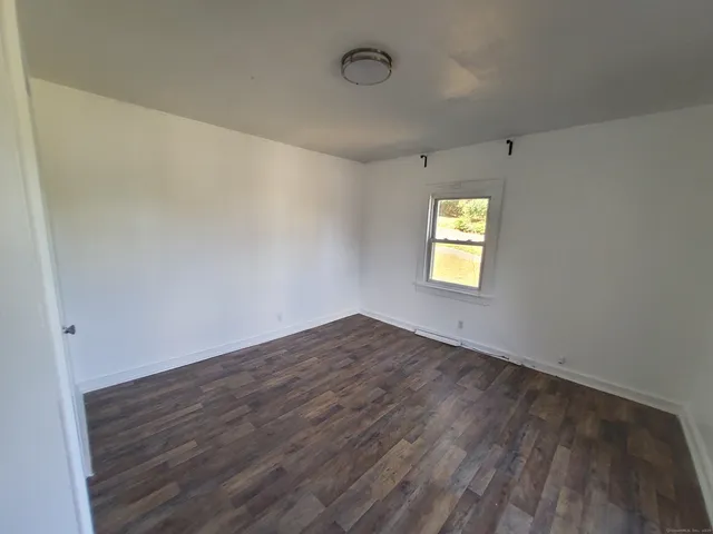 an empty room with wooden floor and window