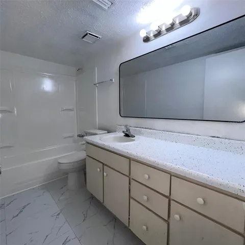 a bathroom with a granite countertop sink a toilet and bathtub