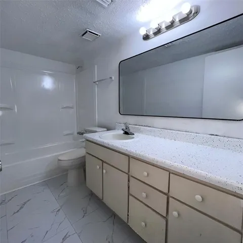 a bathroom with a granite countertop sink a toilet and bathtub
