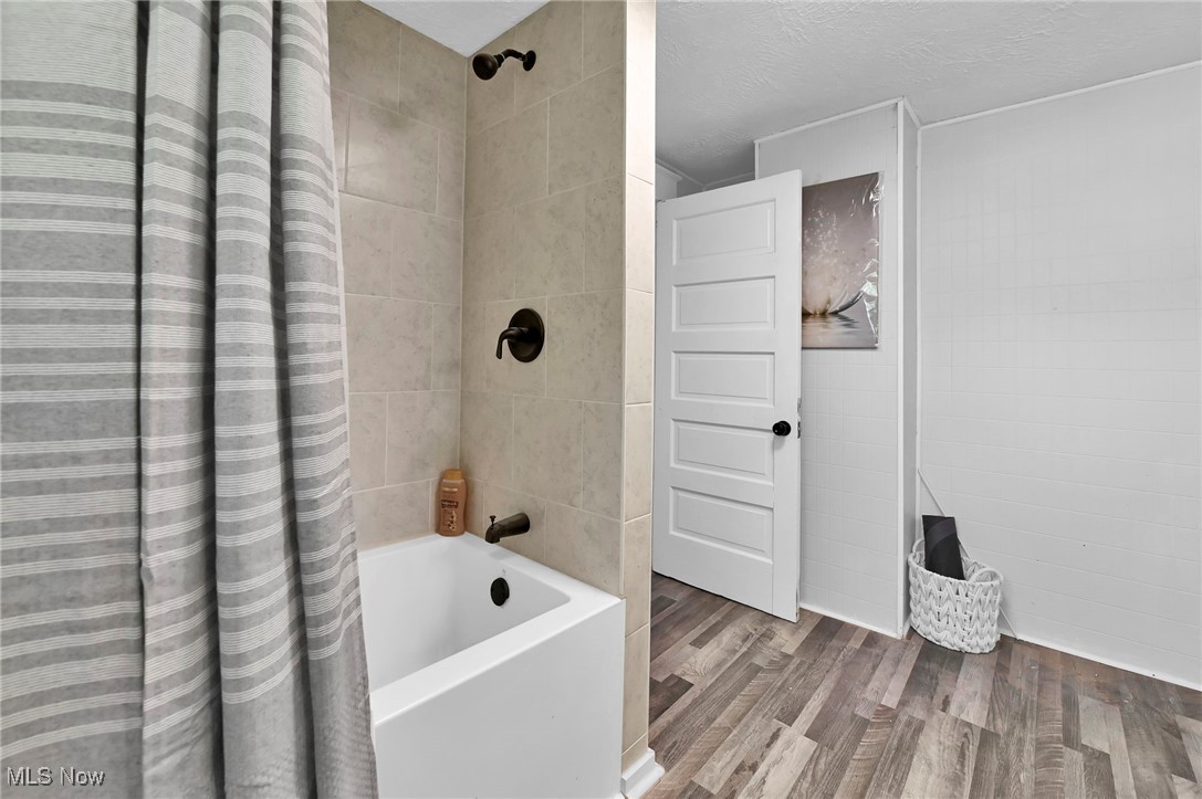 732 Carpenter Street Akron, OH 44310 - Photo 30 of 38 Bathroom featuring shower / bath combo, wood finished floors, a textured ceiling, and tile walls