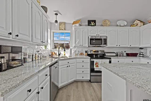 a kitchen with cabinets appliances a sink and a counter top space