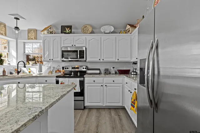 a kitchen with stainless steel appliances granite countertop a stove a sink and a refrigerator