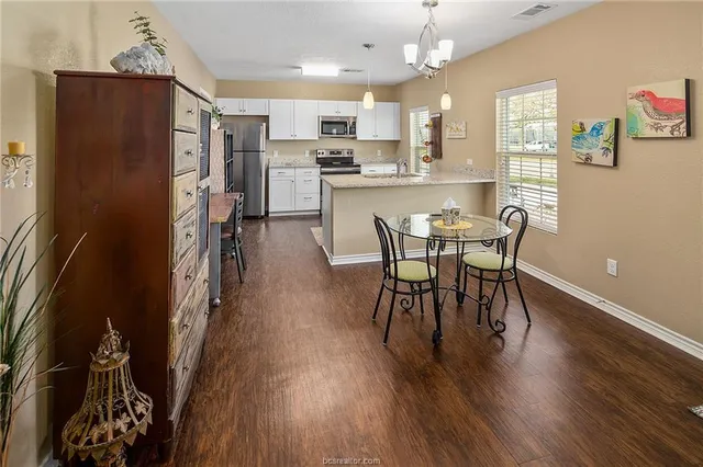 a kitchen with stainless steel appliances a dining table chairs and wooden floor