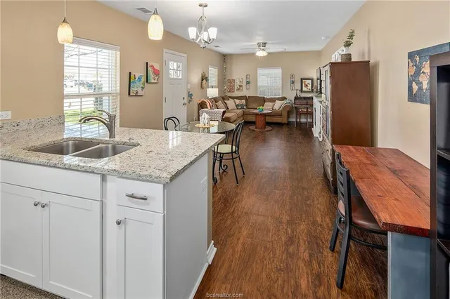 a kitchen with stainless steel appliances granite countertop a refrigerator a sink dishwasher a stove and white countertops with wooden floor