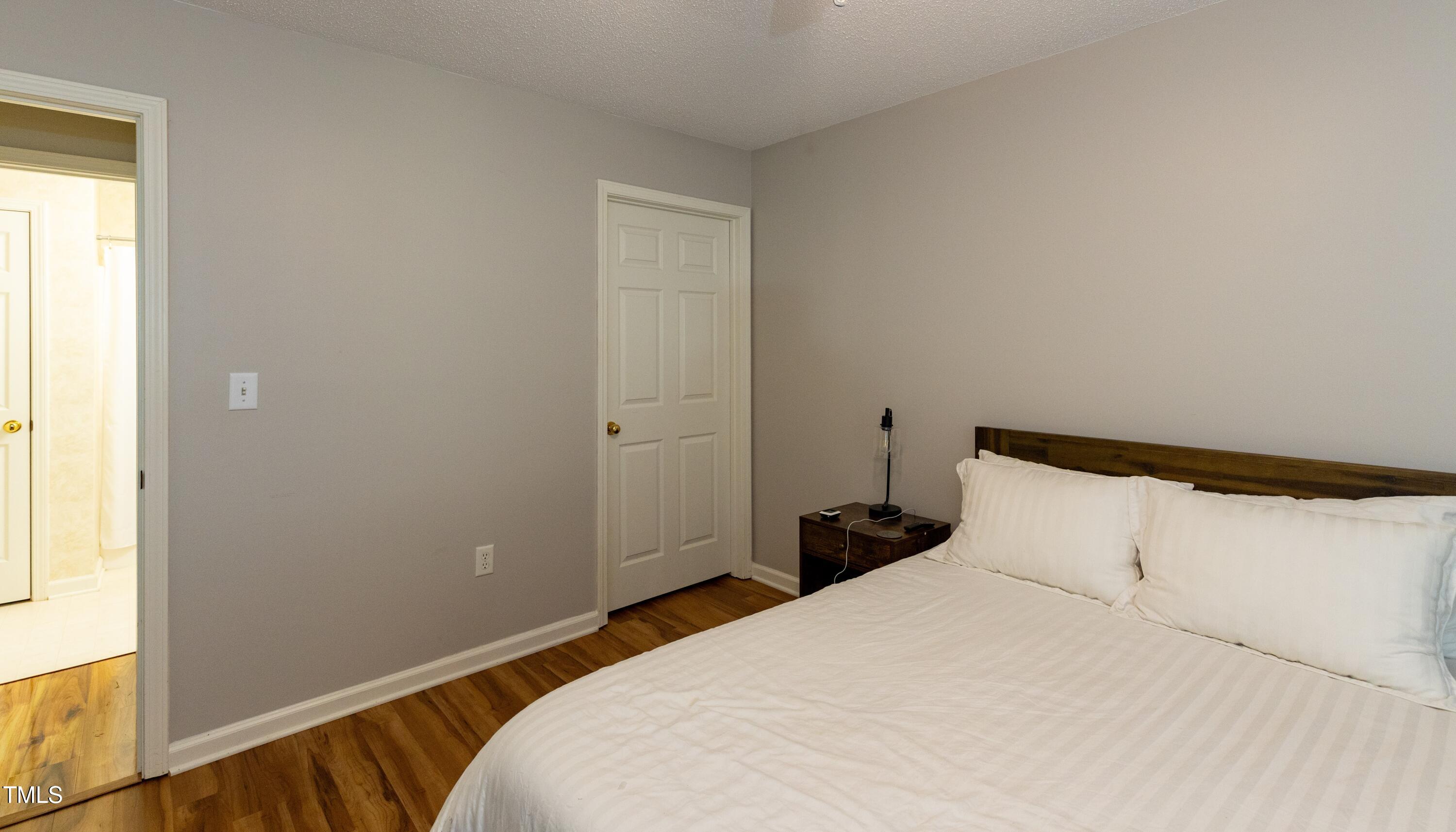 1911 Falls Landing Drive, Unit 103 Raleigh, NC 27614 - Photo 19 of 28 a bedroom with a bed and wooden floor