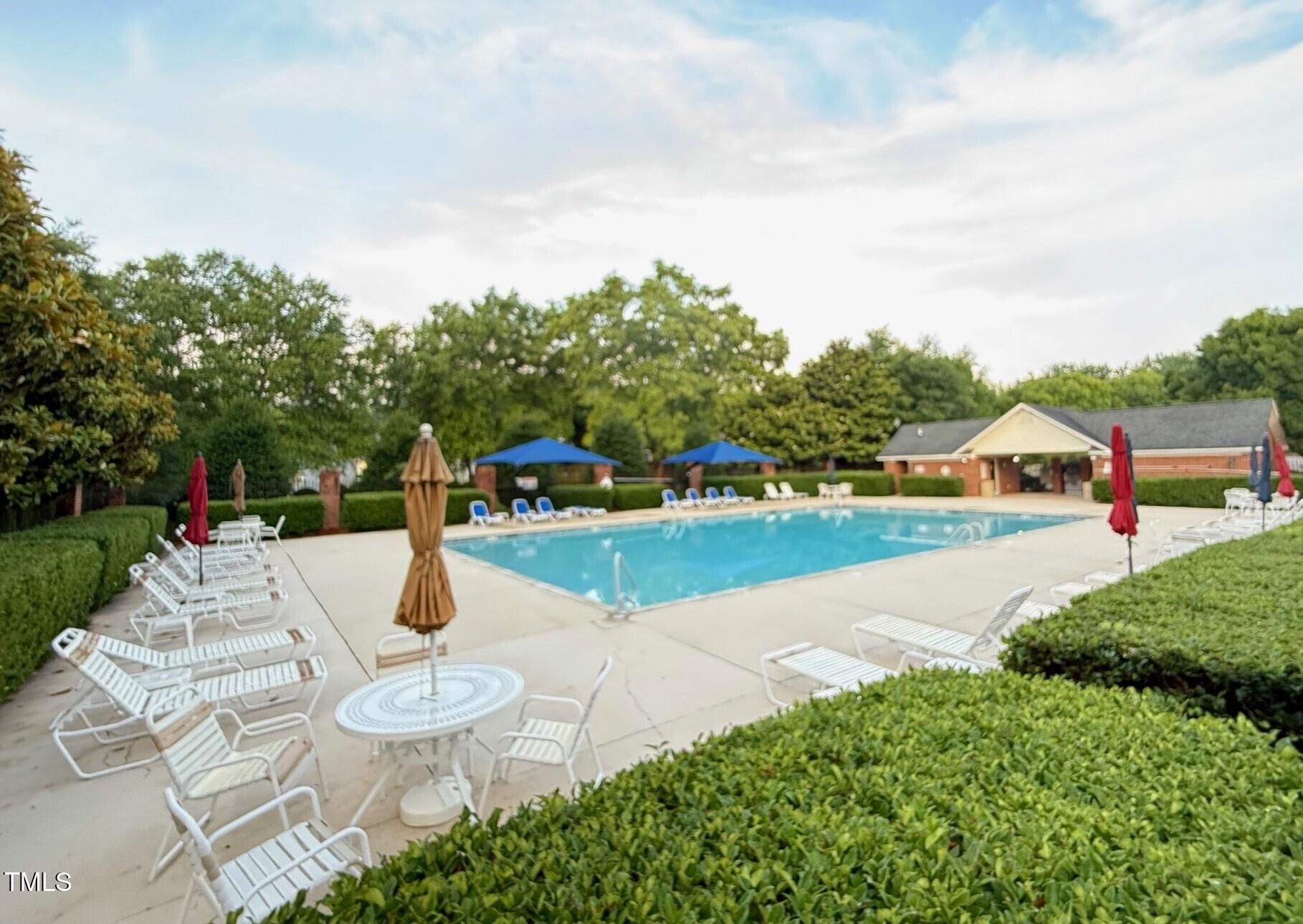 1911 Falls Landing Drive, Unit 103 Raleigh, NC 27614 - Photo 27 of 28 a white house with a yard and table and chairs under an umbrella