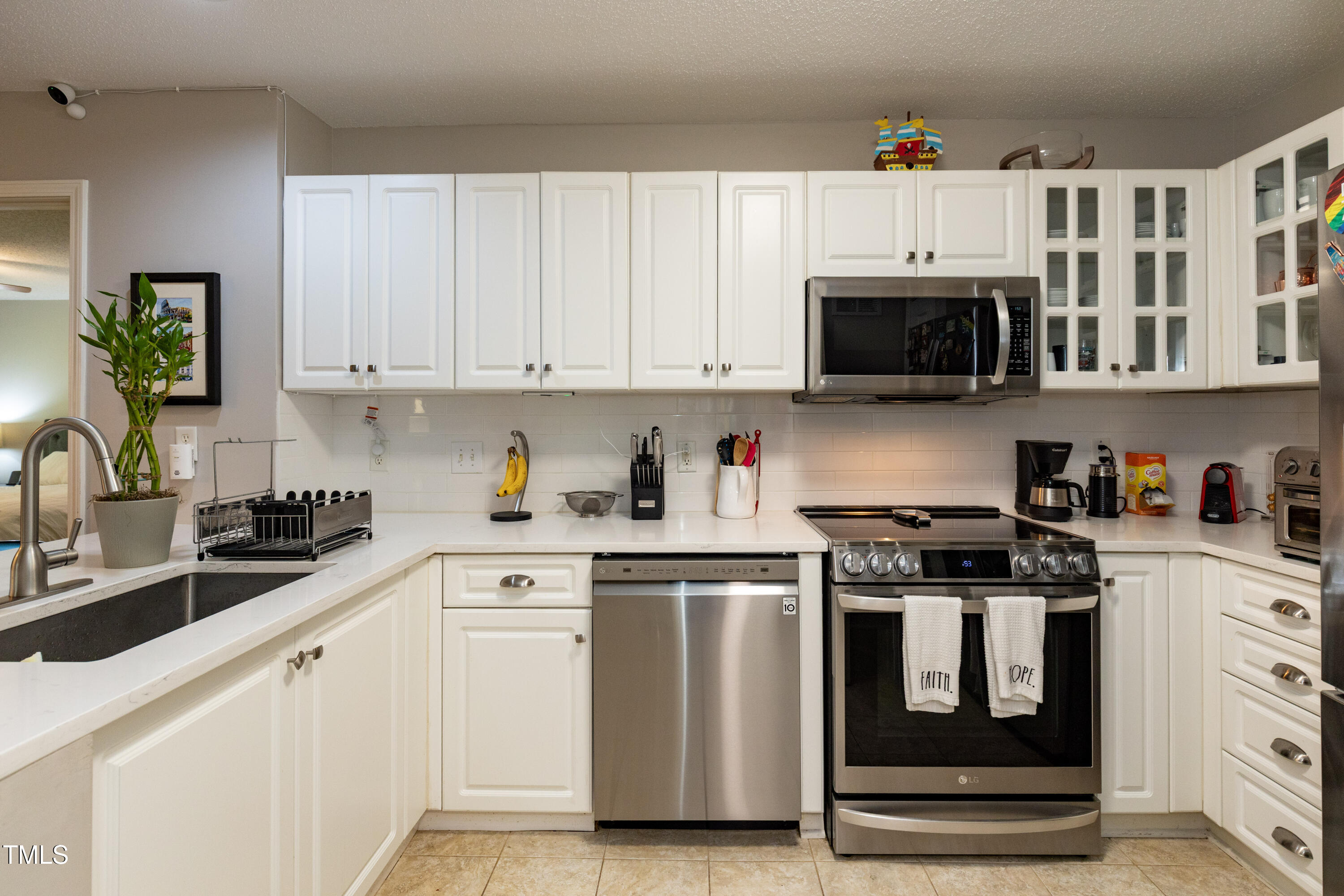 1911 Falls Landing Drive, Unit 103 Raleigh, NC 27614 - Photo 8 of 28 a kitchen with stainless steel appliances granite countertop a stove a sink and white cabinets