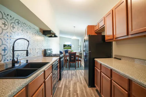 a kitchen with stainless steel appliances granite countertop a sink a stove and refrigerator