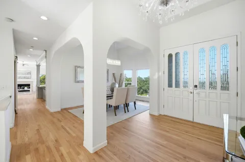 a view of a hallway with wooden floor and a chandelier