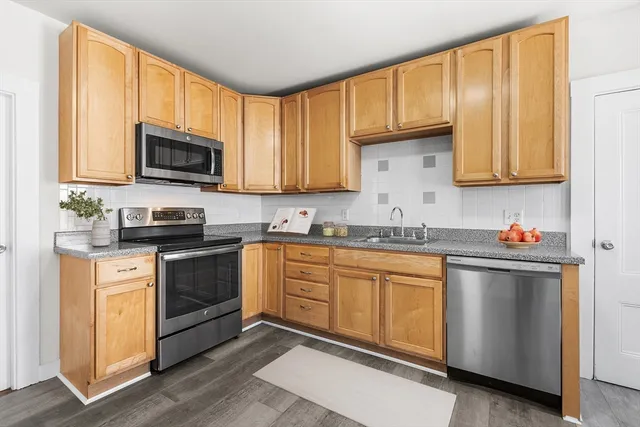 a kitchen with granite countertop wood cabinets stainless steel appliances and a window