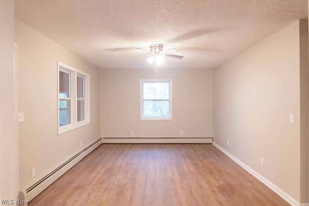 3644 Padanarum Road Geneva, OH 44041 - Photo 4 of 19 Spacious room featuring wood-finish flooring, neutral painted walls, two windows with white trim, and a ceiling fan with integrated lighting