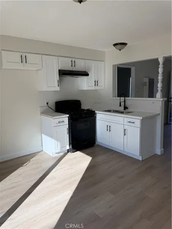 a kitchen with a sink dishwasher a stove and white cabinets