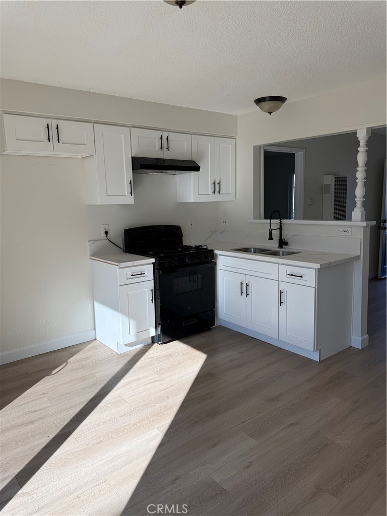 558 South Benjamin Street Rialto, CA 92376 - Photo 12 of 25 a kitchen with a sink dishwasher a stove and white cabinets
