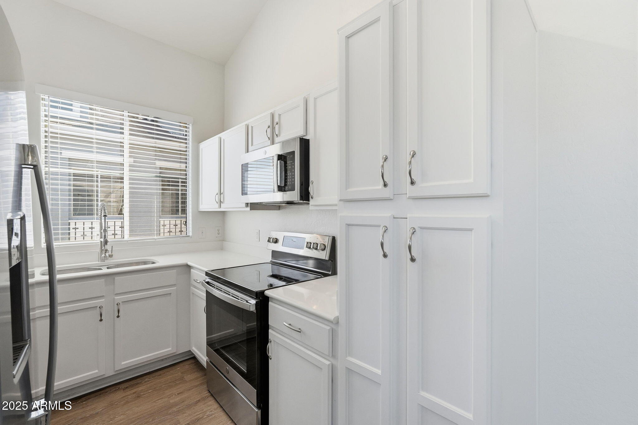 9233 East Neville Avenue, Unit 1136 Mesa, AZ 85209 - Photo 6 of 29 a white kitchen with stainless steel appliances granite countertop white cabinets and sink