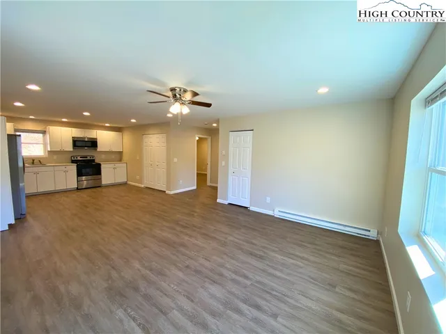 an empty room with wooden floor and a kitchen