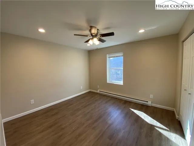an empty room with wooden floor ceiling fan and windows