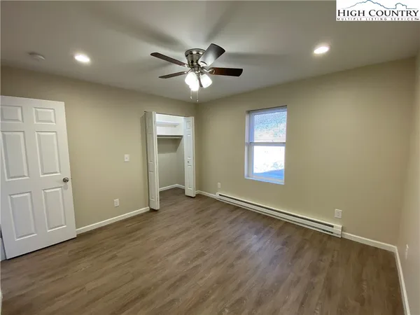 an empty room with wooden floor a ceiling fan and windows