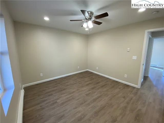 an empty room with wooden floor and a ceiling fan