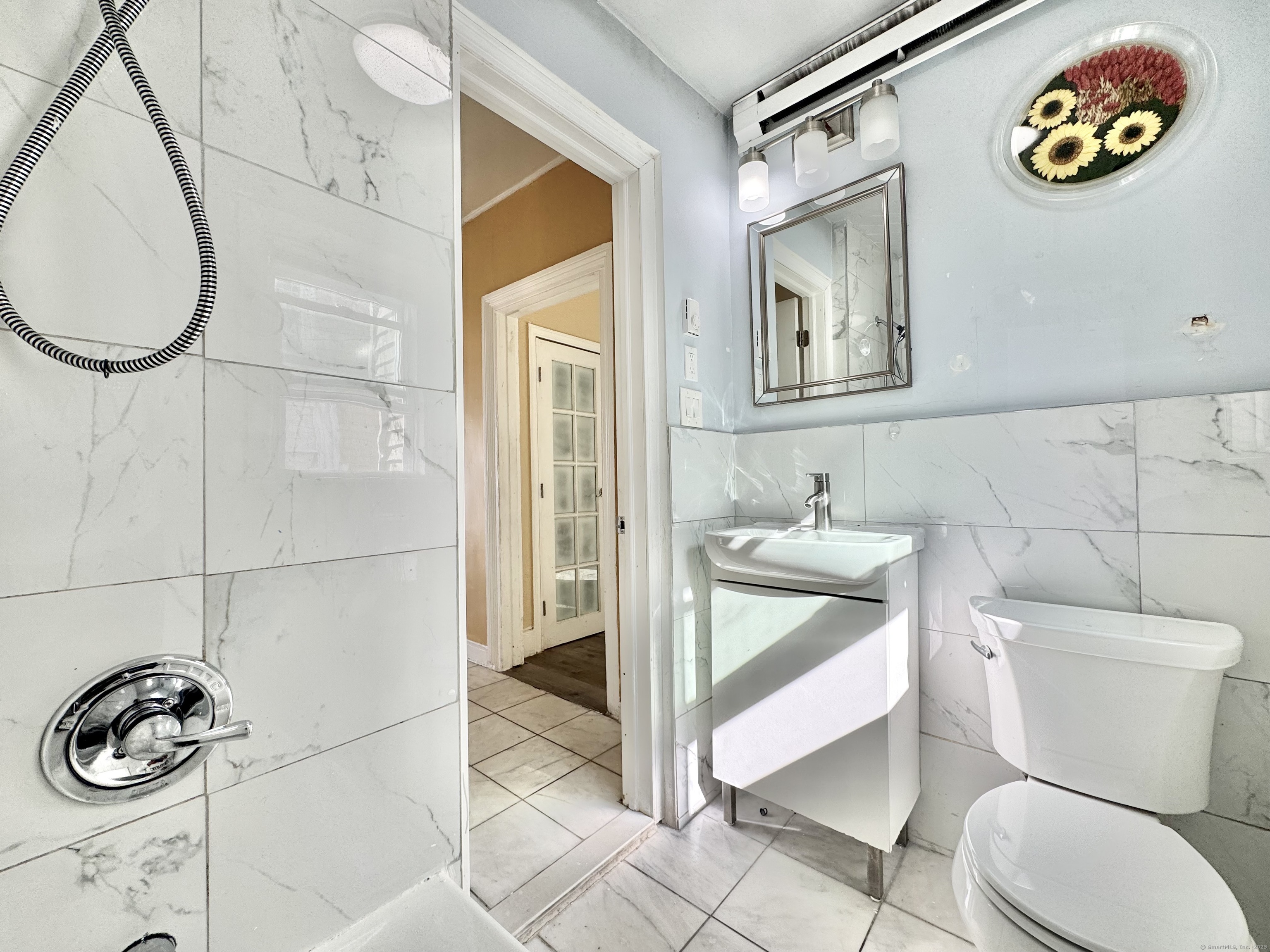 Undisclosed Address Bridgeport, CT 06608 - Photo 9 of 18 a bathroom with a toilet a sink and mirror