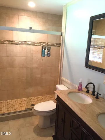 a bathroom with a granite countertop sink toilet a mirror and shower