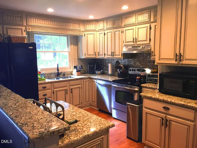 a kitchen with stainless steel appliances granite countertop a stove a sink and a microwave