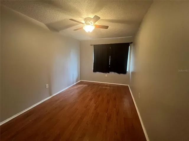 en empty room with wooden floor and fan