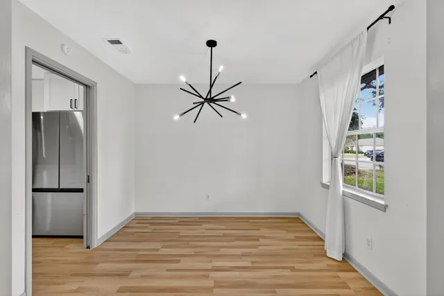 a view of empty room with wooden floor and window