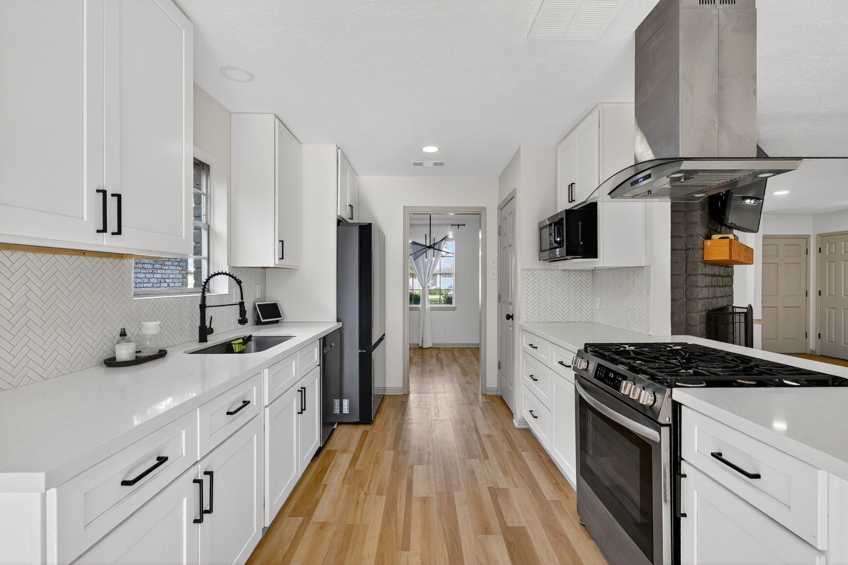 16122 Rill Lane Houston, TX 77062 - Photo 7 of 23 a kitchen with stainless steel appliances a sink stove oven a refrigerator white cabinets and wooden floor